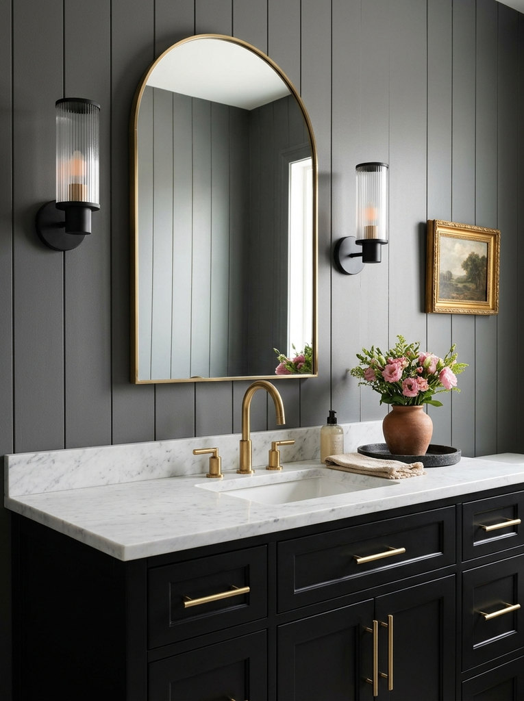 Black bathroom vanity decor with white marble top, brass pulls and arched mirror