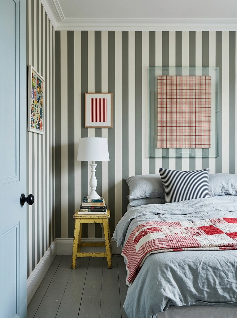 Bedroom with gray-green and white vertical striped walls and a red patchwork quilt